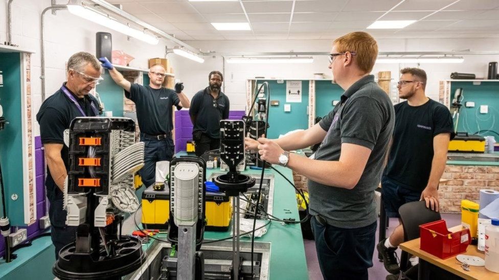 An engineer demonstrates a robotic arm to students in a hands-on training session.