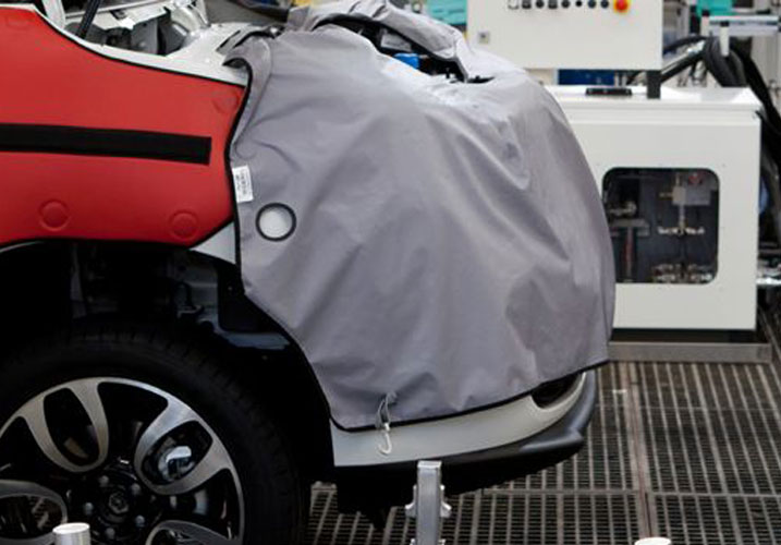 Very close-up of a car undergoing crash testing with safety equipment cover and testing machinery.