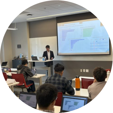 Instructor delivering a research presentation to engaged students in a modern classroom.