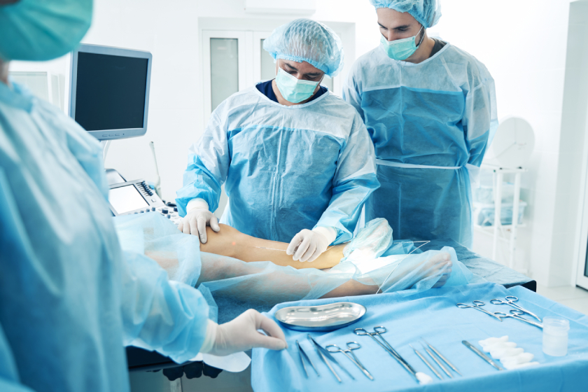 An operating room scene with surgeons in protective gear performing surgery on a patient.