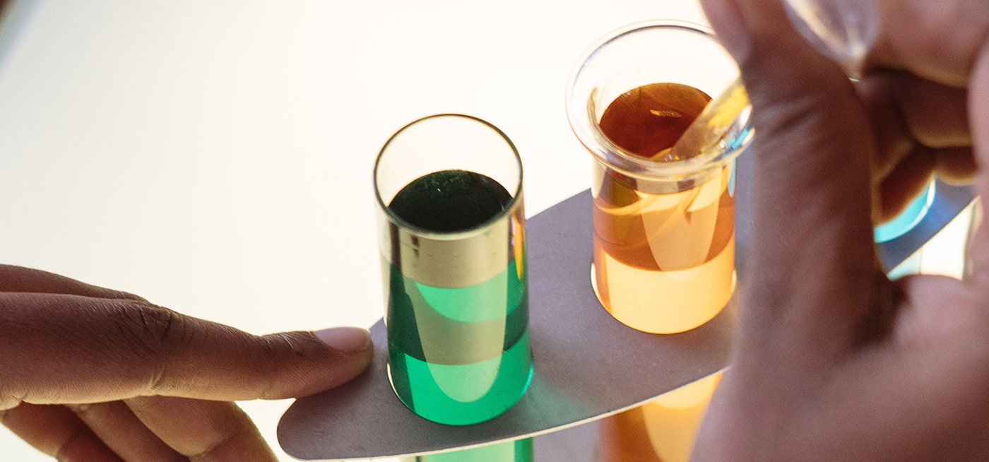 Close-up of a scientist holding a laboratory tray with test tubes filled with colorful liquids for scientific research.