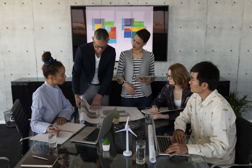 A diverse team reviews project planning and research strategies in a modern office.