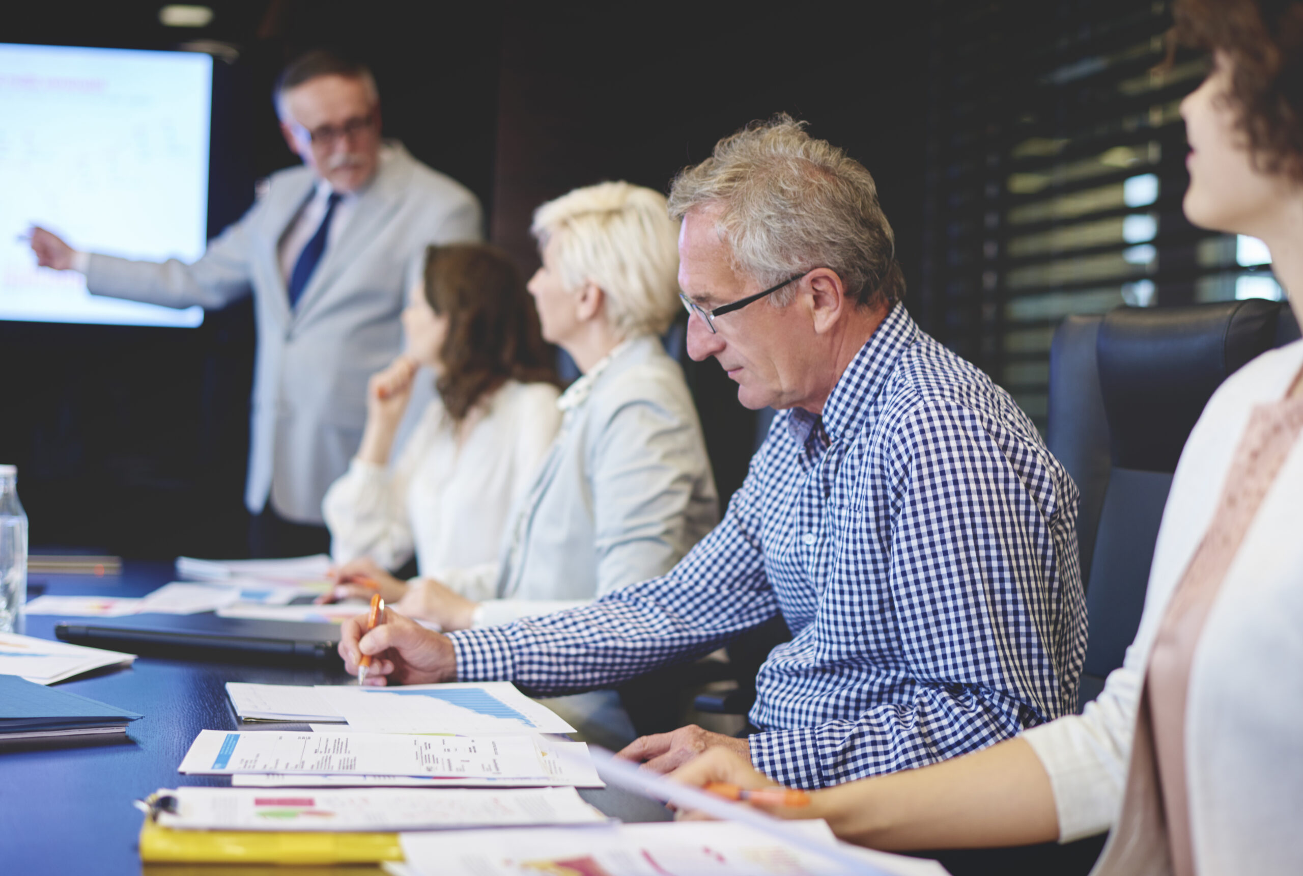 Analyzing research papers at academic conference with researchers discussing journal publishing.