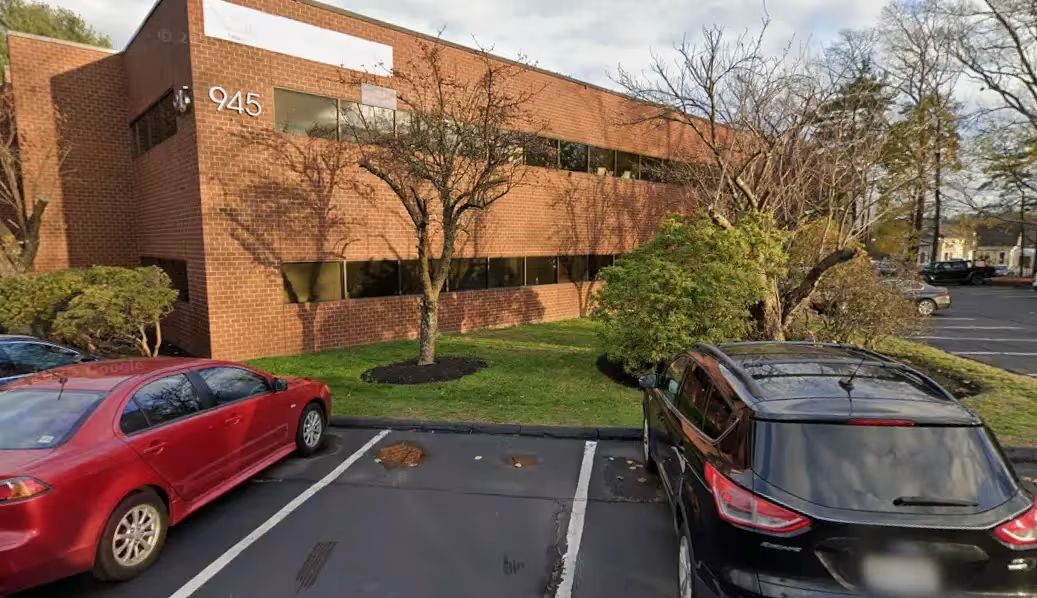 Office building exterior with parking lot and trees.