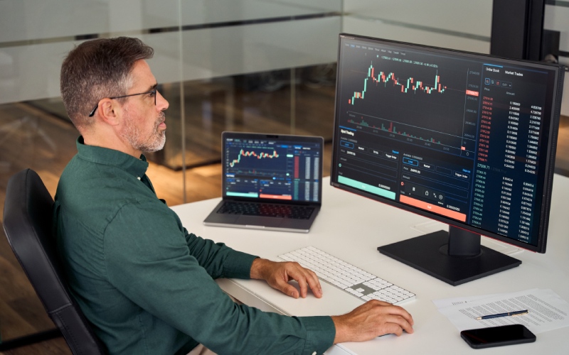 Stock market analysis with multiple screens showing financial data and charts.
