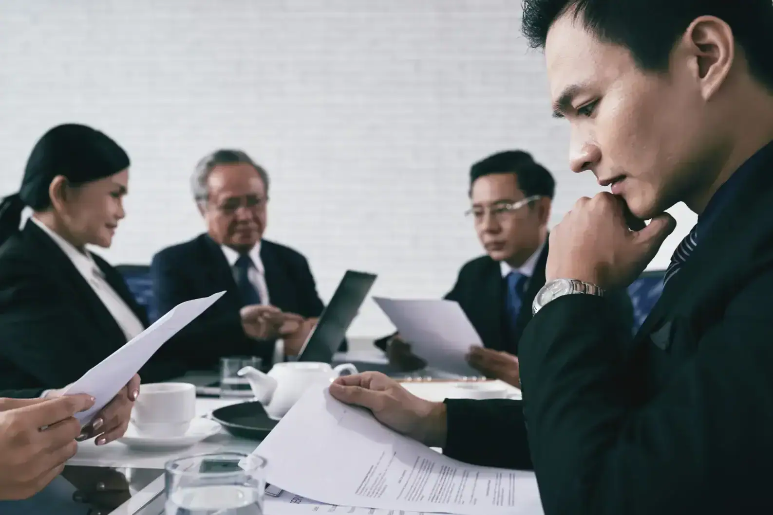 Board of directors reviewing documents in a professional business meeting.