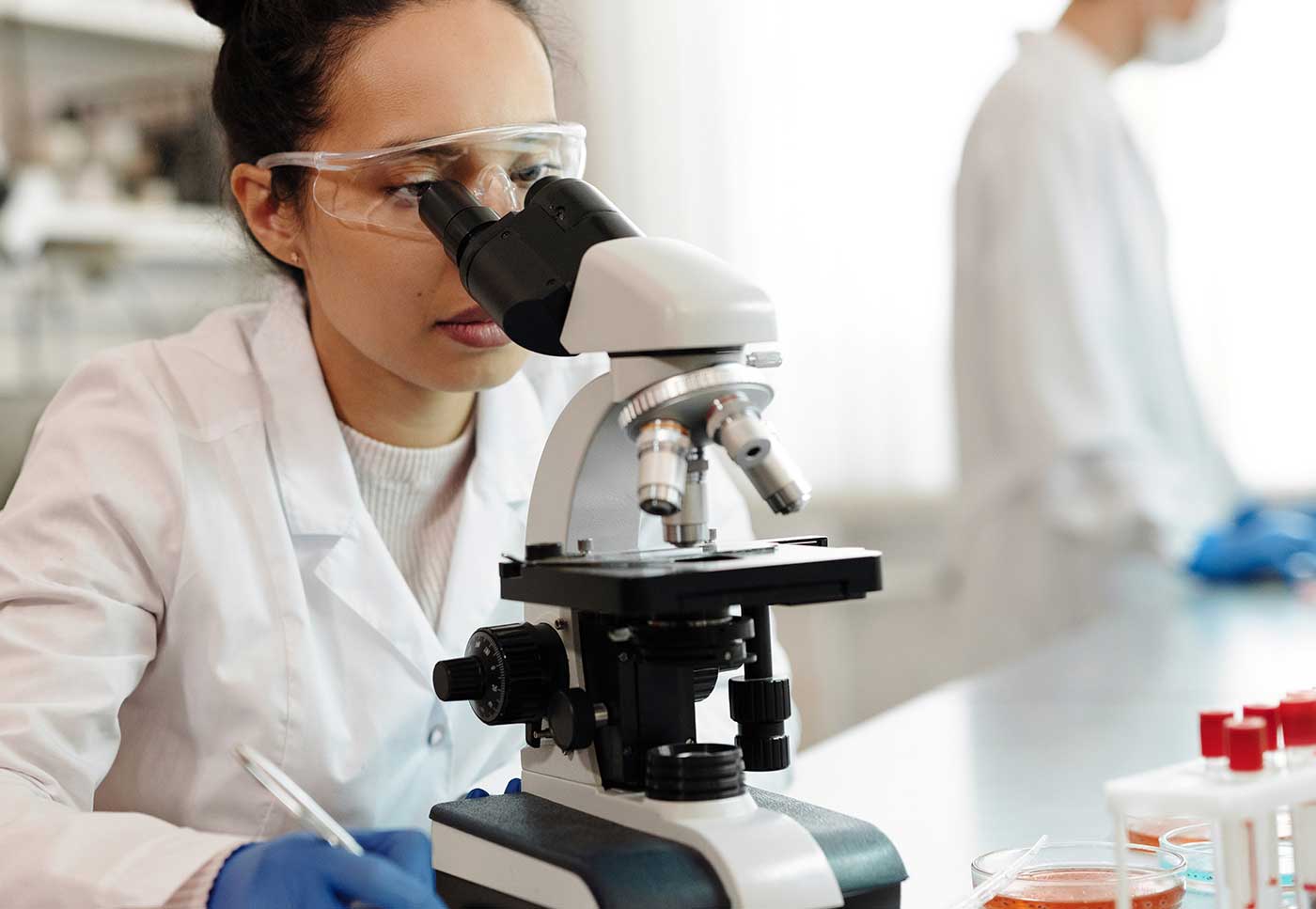 Microscope, research, and female scientist in laboratory focusing on scientific research and medical studies.