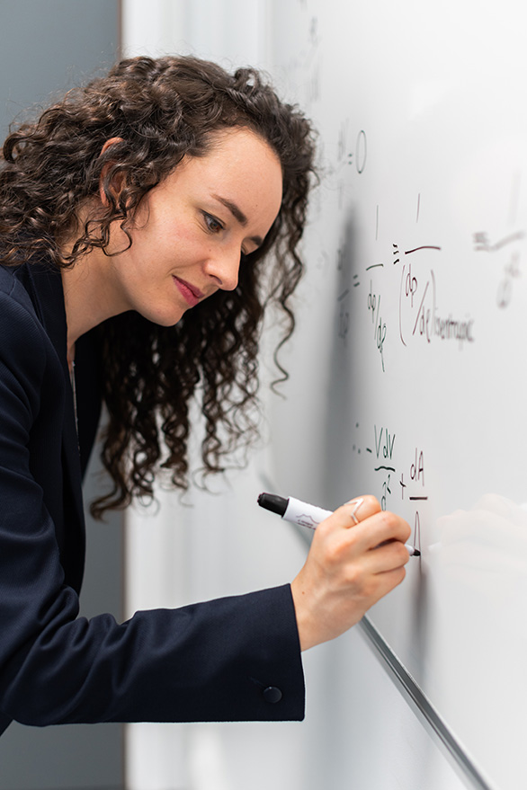 Whiteboard with mathematical formulas and research data in academic setting.