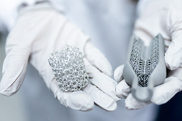 High-resolution image showing researchers handling complex metal 3D-printed lattice structures.