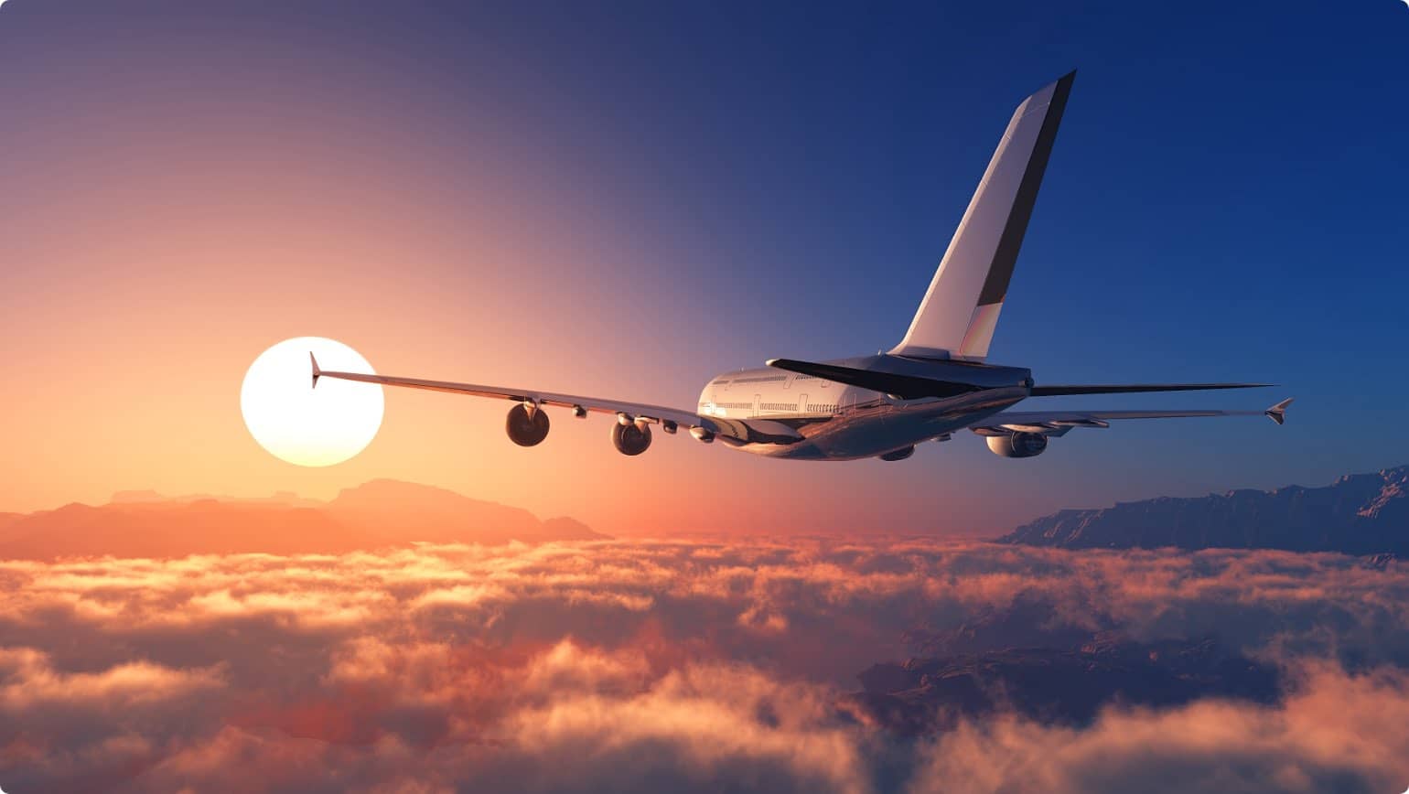 A commercial airplane flying high above clouds during sunset, representing air travel and aviation industry.