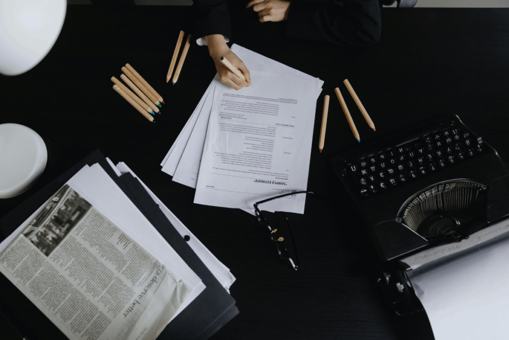 Handwriting on document pages with pens and typewriter on desk.