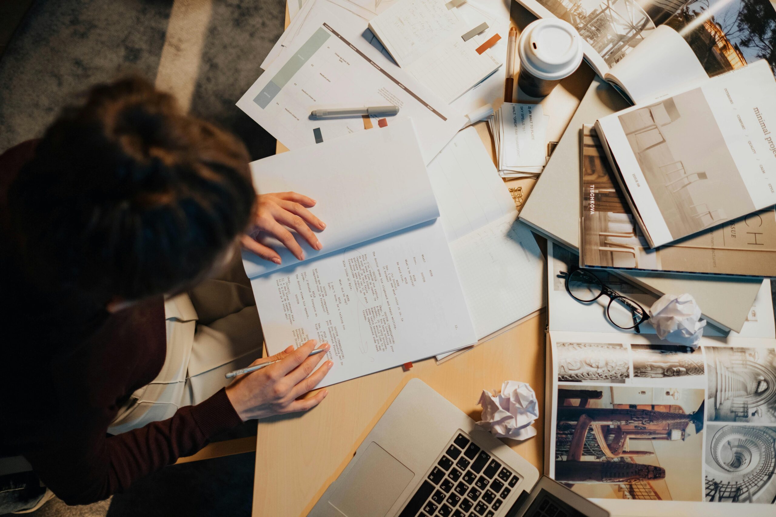 Close-up of a researcher working on academic papers and reports at a cluttered desk.