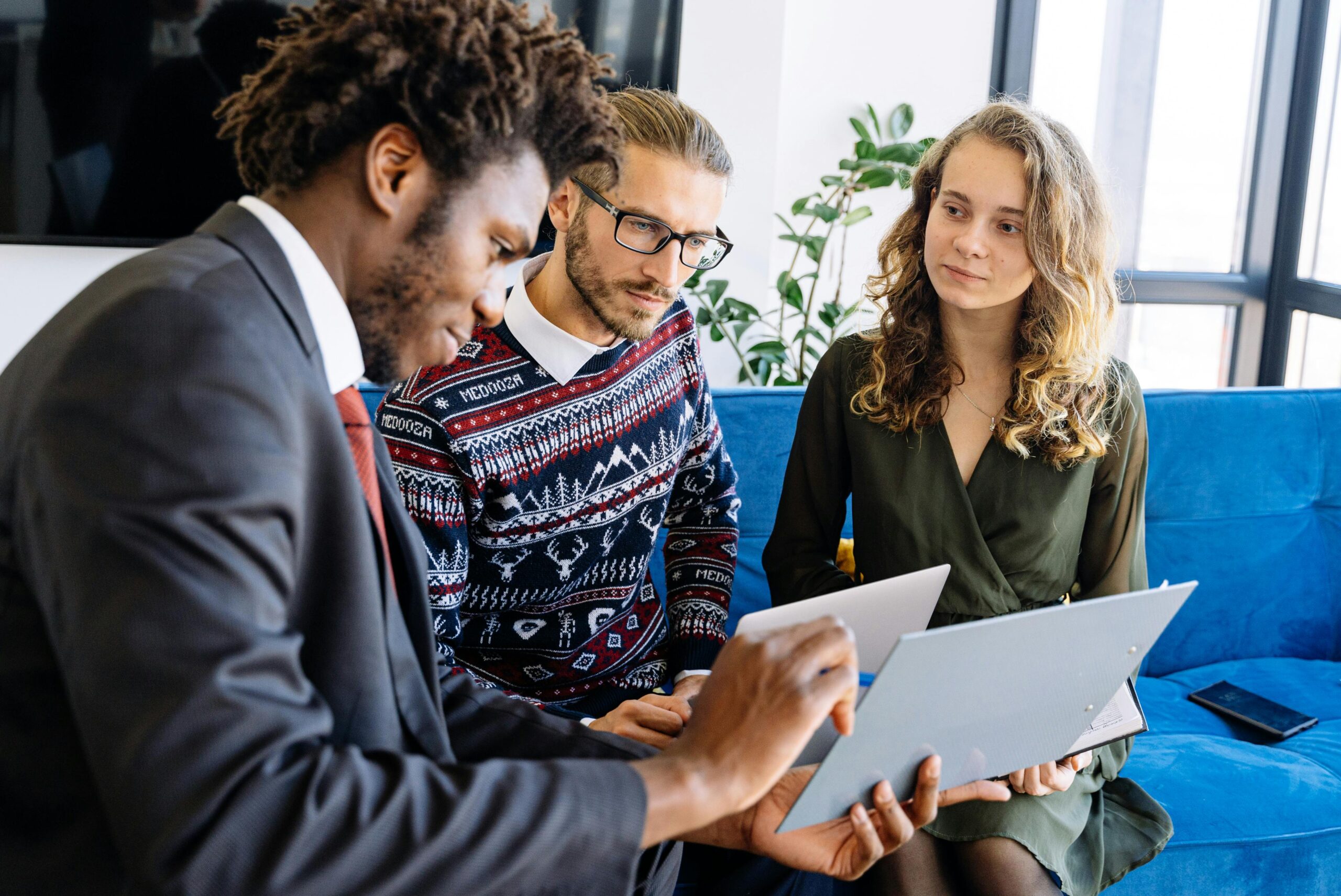 African American man, white man, and woman discussing research data in a modern office setting, emphasizing diversity and teamwork in academia.
