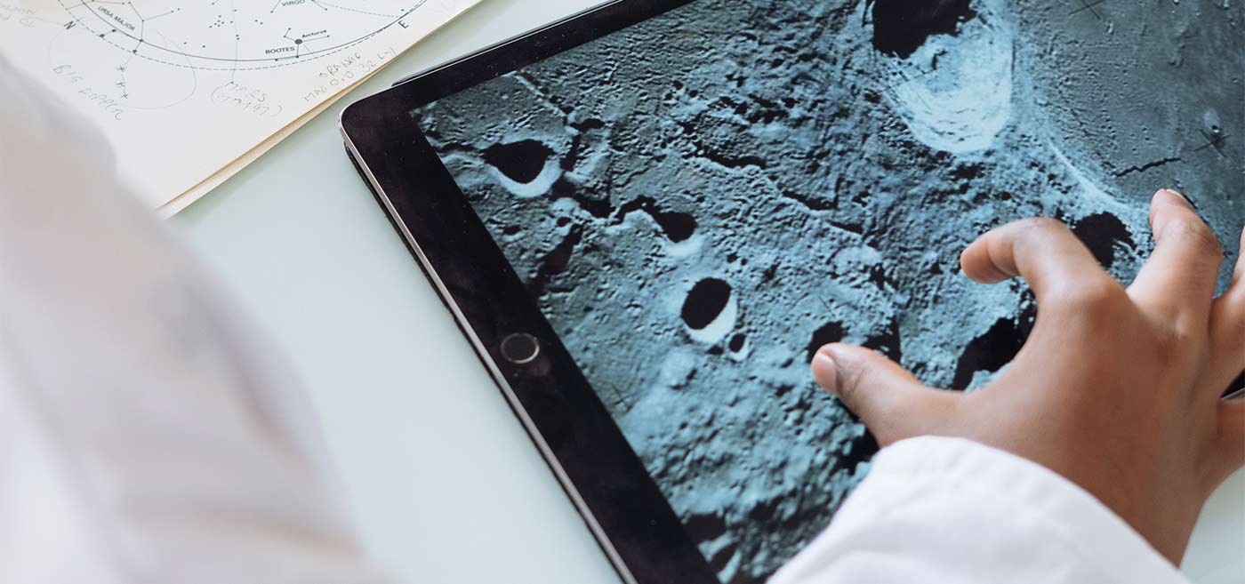 Close-up of a person examining lunar craters on a tablet screen for scientific research.