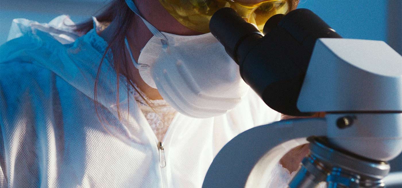 Scientist examining samples using a microscope.