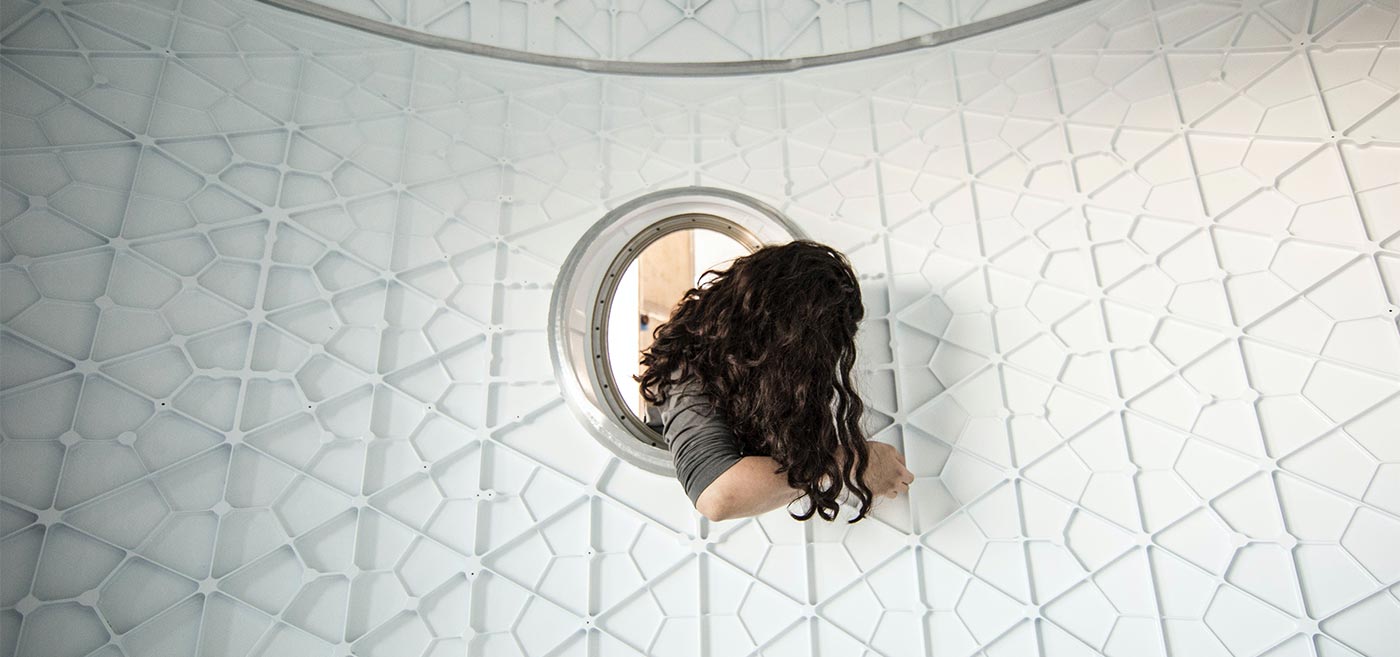 A woman with curly hair emerging from a spacecraft hatch.