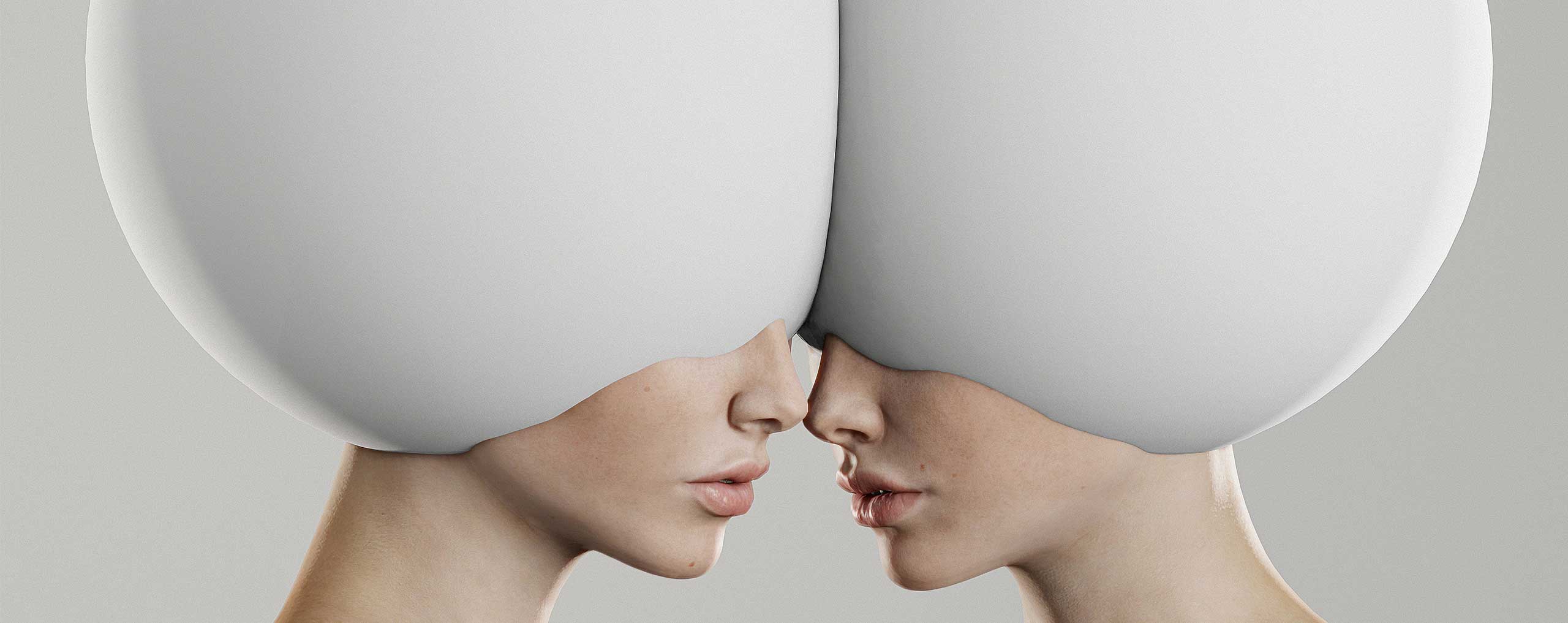 Close-up of two women touching foreheads under large white spherical objects on their heads, emphasizing communication and connection.