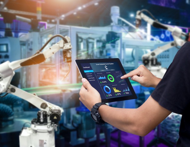 Robotics automation in advanced manufacturing with real-time data analysis on a tablet.