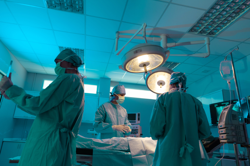 Medical professionals performing surgery in sterile hospital operating room.