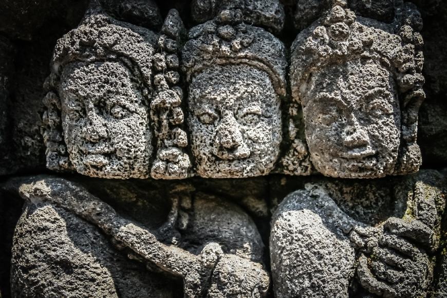 Ancient Mayan stone carvings depicting three figures with detailed facial features and traditional a.